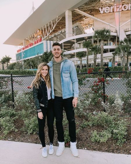Meyers Leonard and wife Elle Leonard pose a picture in front of a stadium.